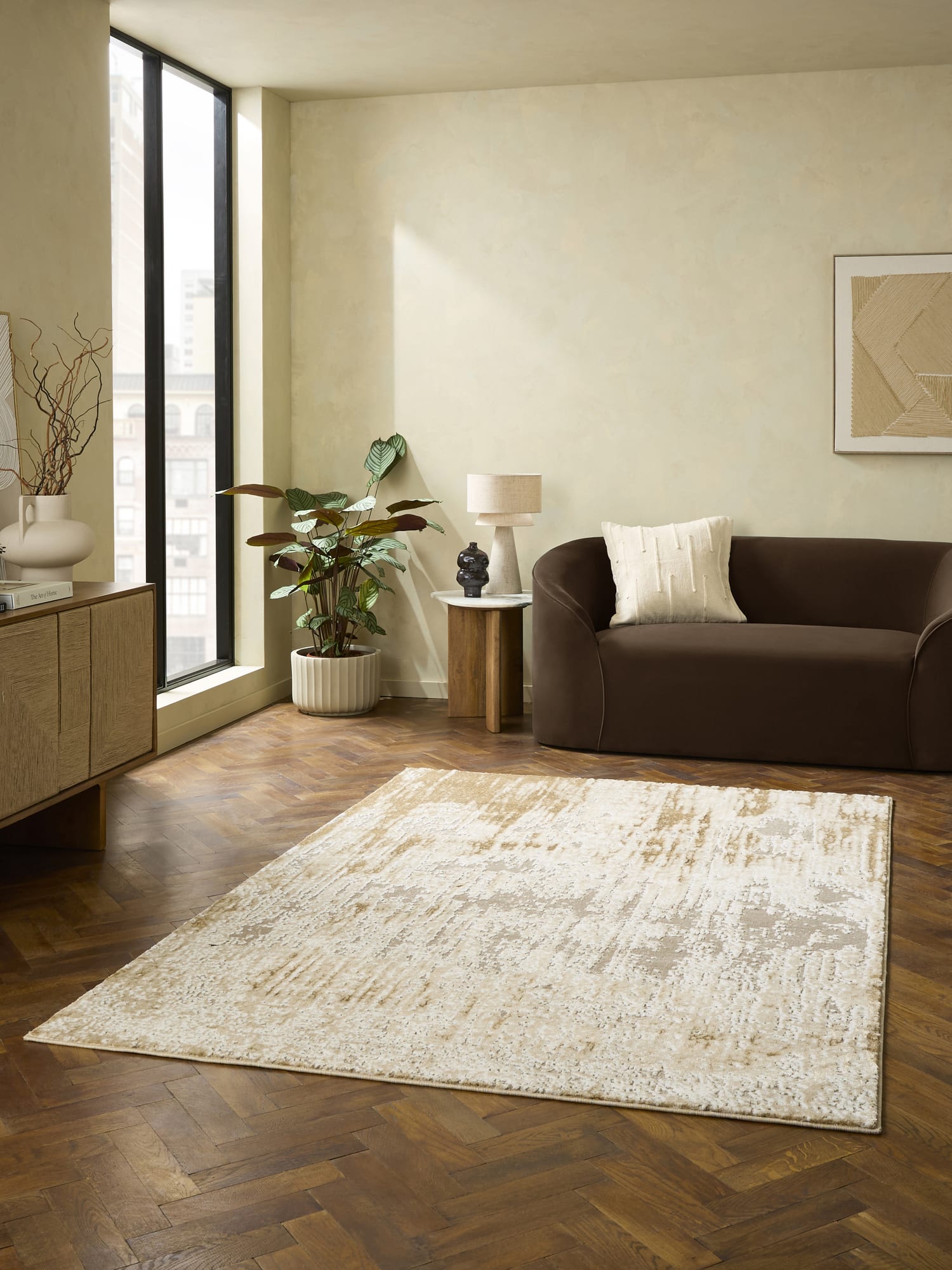 Apollo rectangular rug in cream and beige, in front of a brown sofa on a parquet floor.