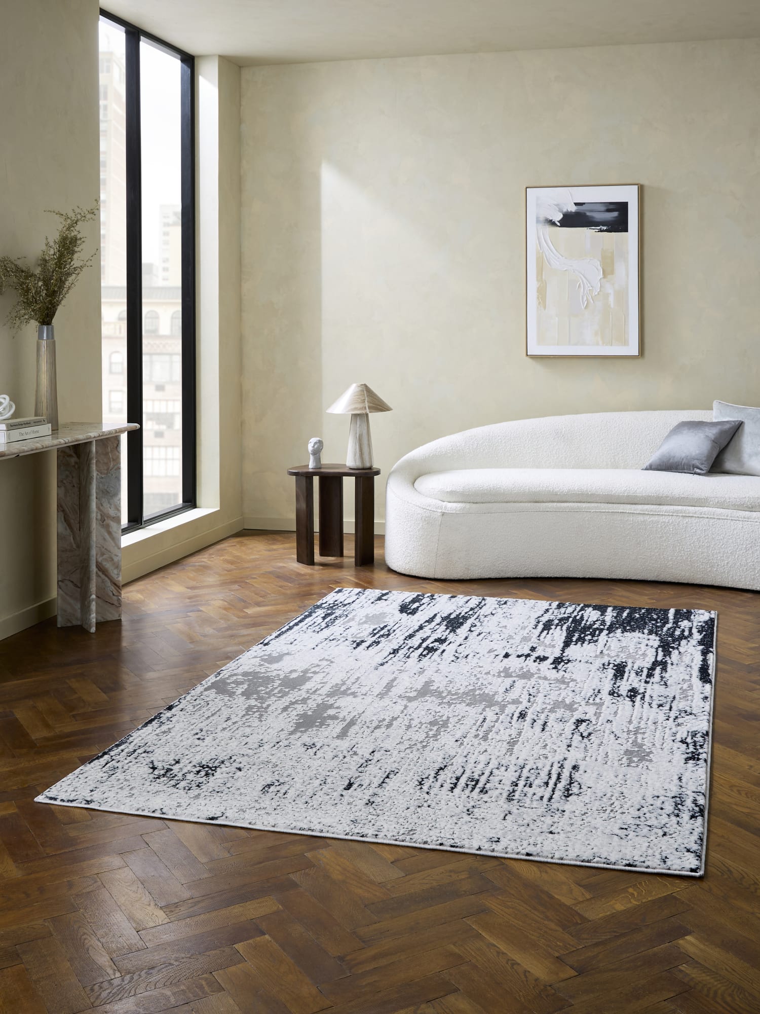 Apollo rectangular rug in grey and navy, in front of a pale curved sofa.