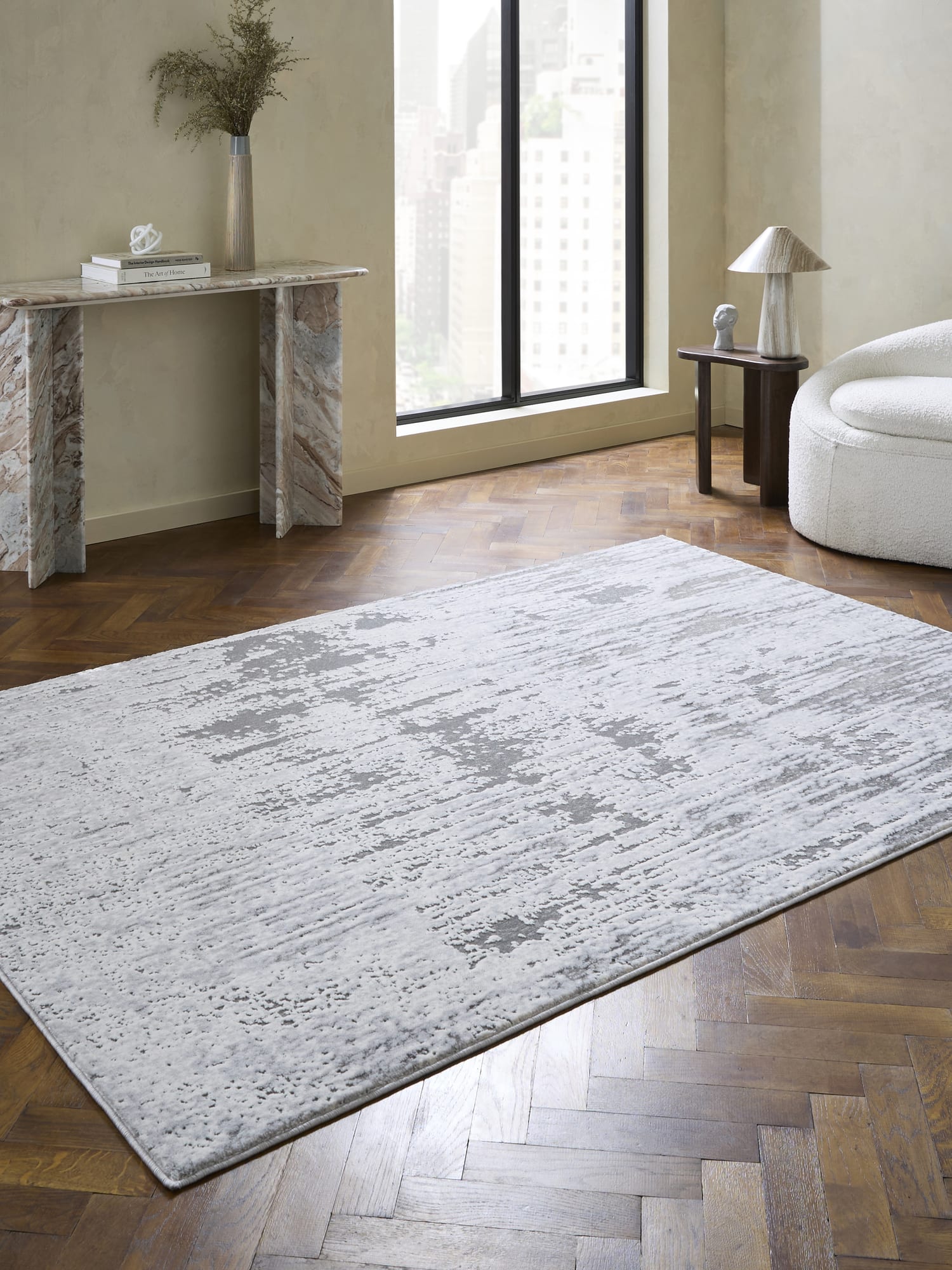 Apollo rectangular rug in grey and silver, beside a console table and a tall window.