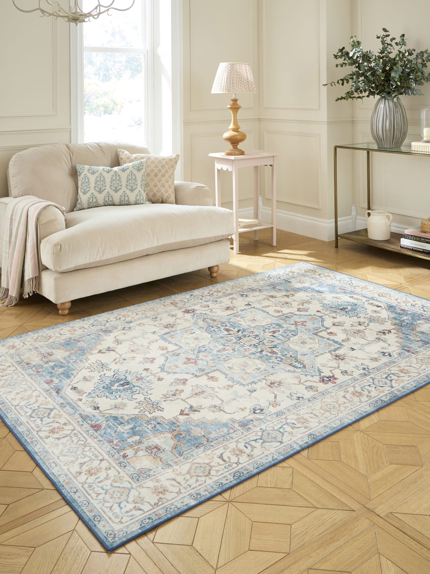 Bohemia rectangular rug in cream and blue, at an angle beside a cream sofa.