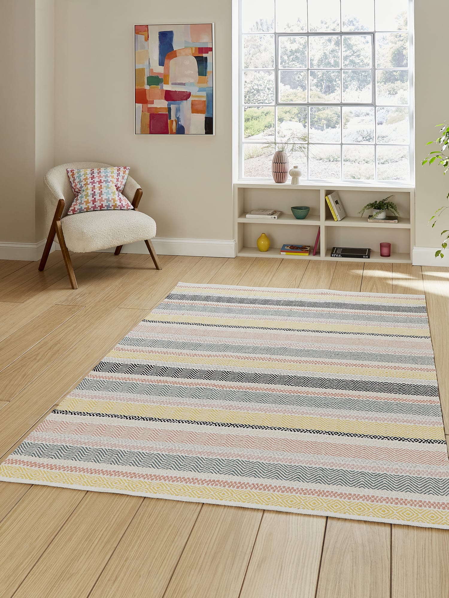 Cascade Pastel Multi Striped Cotton Rug. Cascade rectangular rug in pastel mixed colours, beside an armchair and a large window.