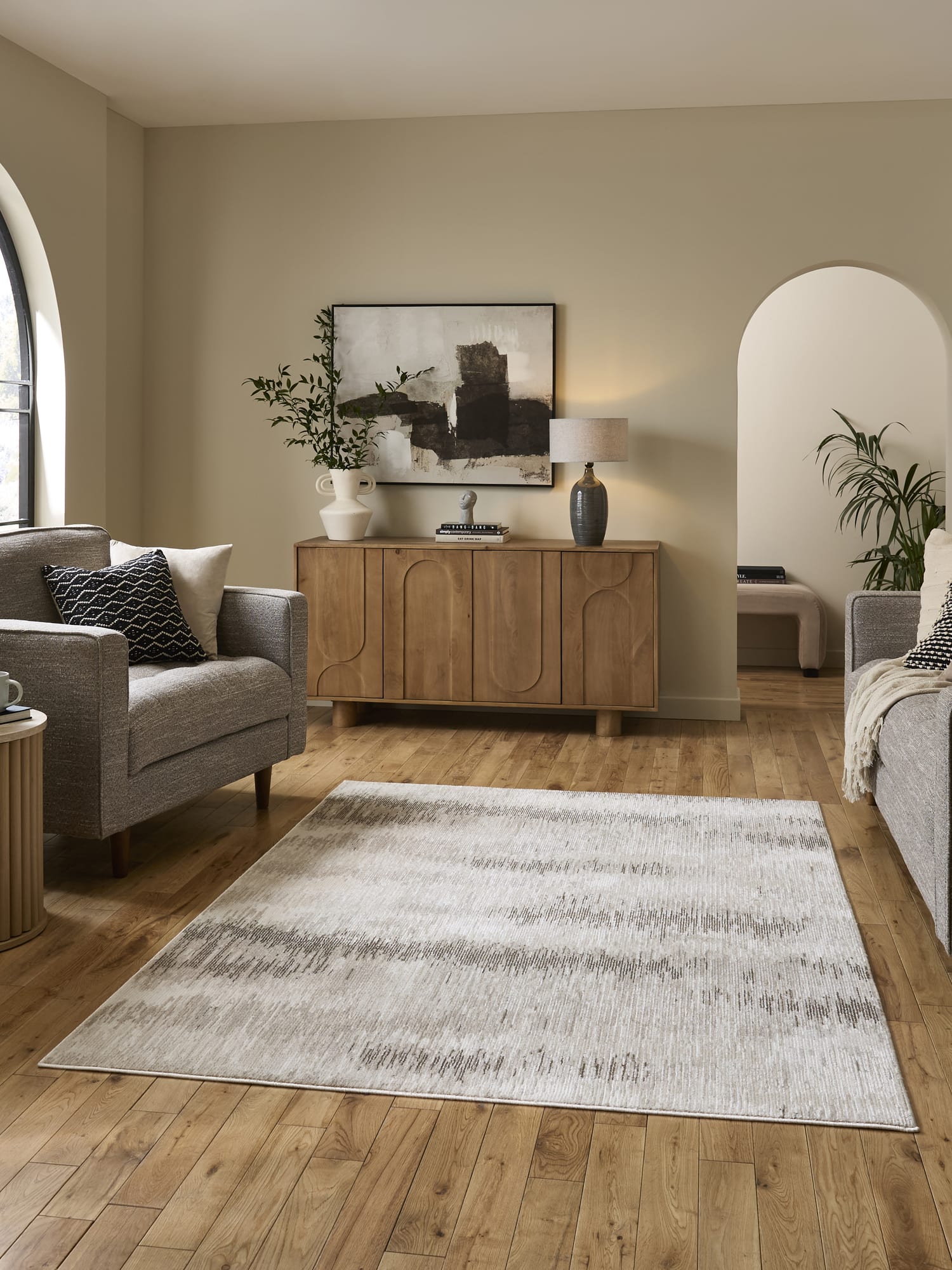 Drift rectangular rug in cream and beige, in a room with a wooden sideboard and pale walls.