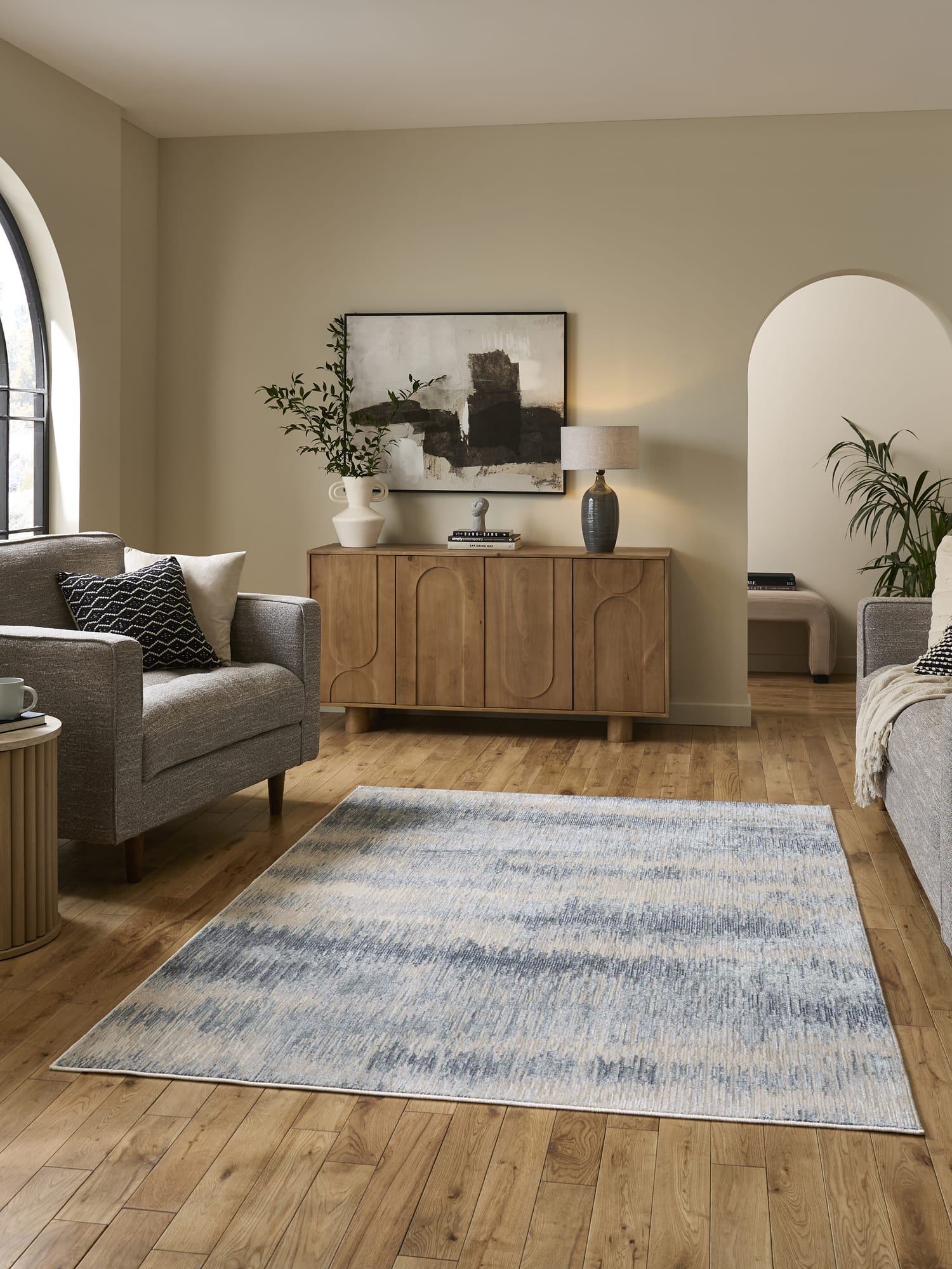 Drift rectangular rug in cream and blue, in a room with a wooden sideboard and pale walls.