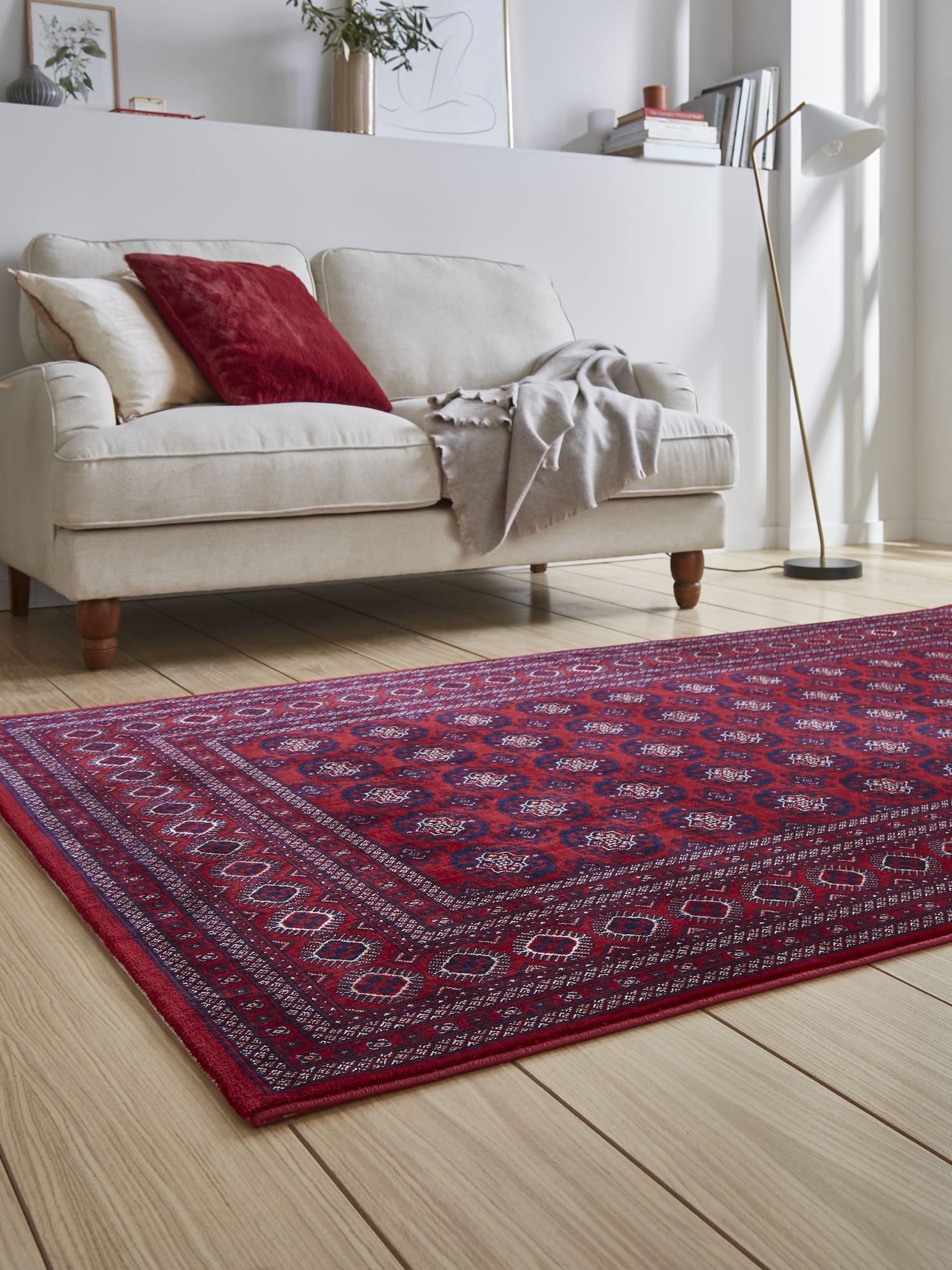 Dubai Diamond Border rectangular rug in red, at a low angle in front of a pale sofa.
