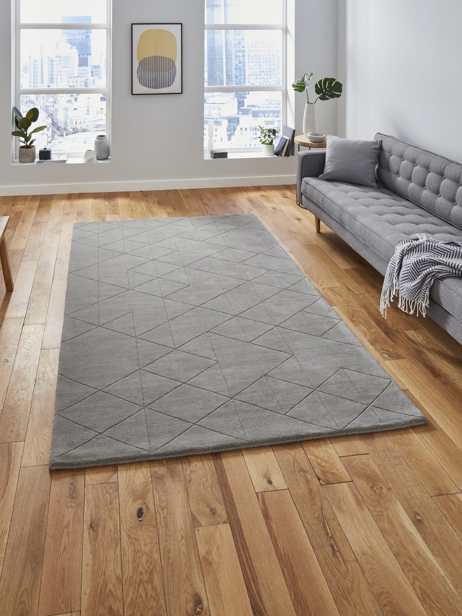 Kasbah rectangular rug in grey, beside a grey sofa on a wooden floor.