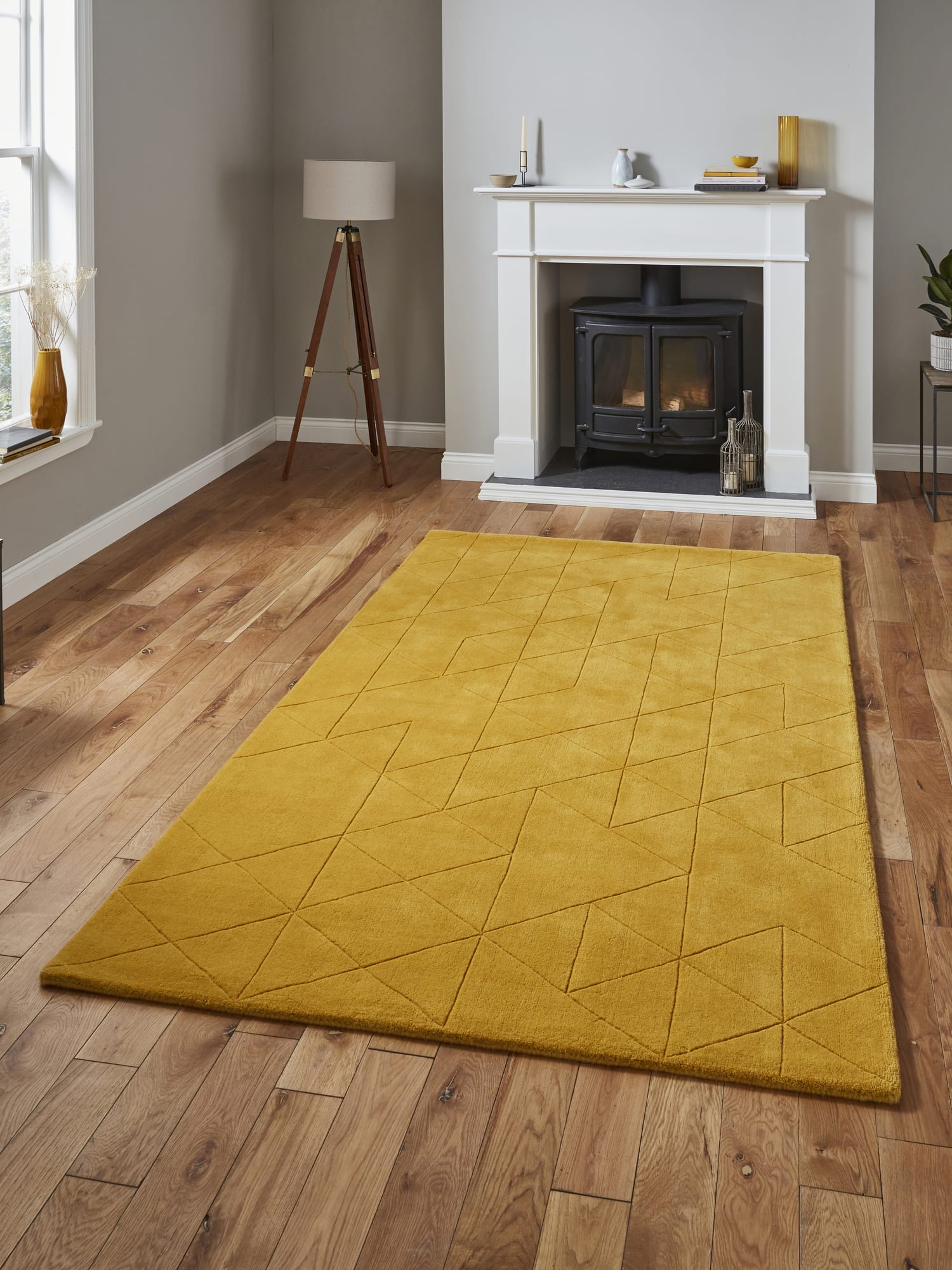 Kasbah rectangular rug in ochre, on a wooden floor in front of a fireplace.