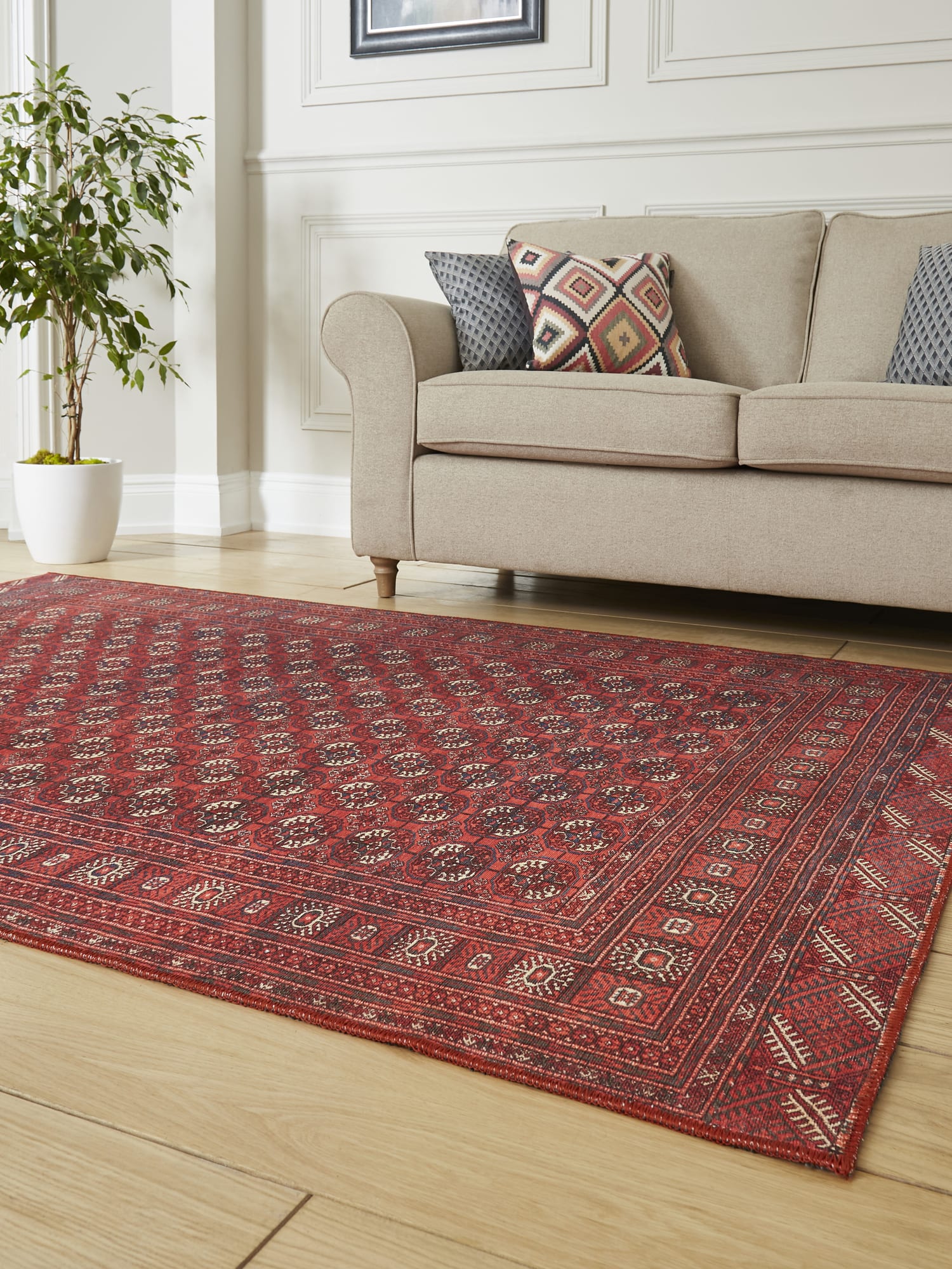Kashmar Geometric Rows rectangular rug in red, at an angle beside a pale sofa.