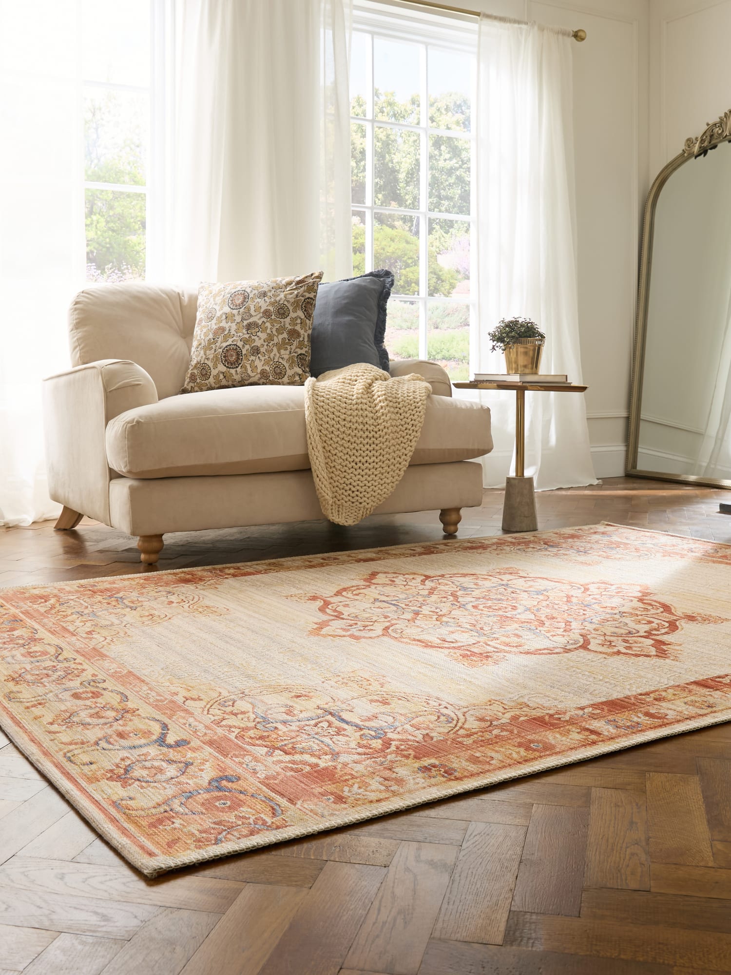 Quartz rectangular rug in cream and rust, beside a cream armchair and a tall mirror.