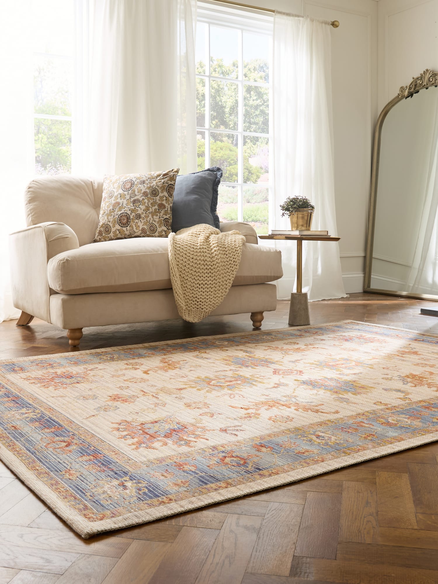 Quartz rectangular rug in ivory and blue, beside a cream armchair and a tall mirror.