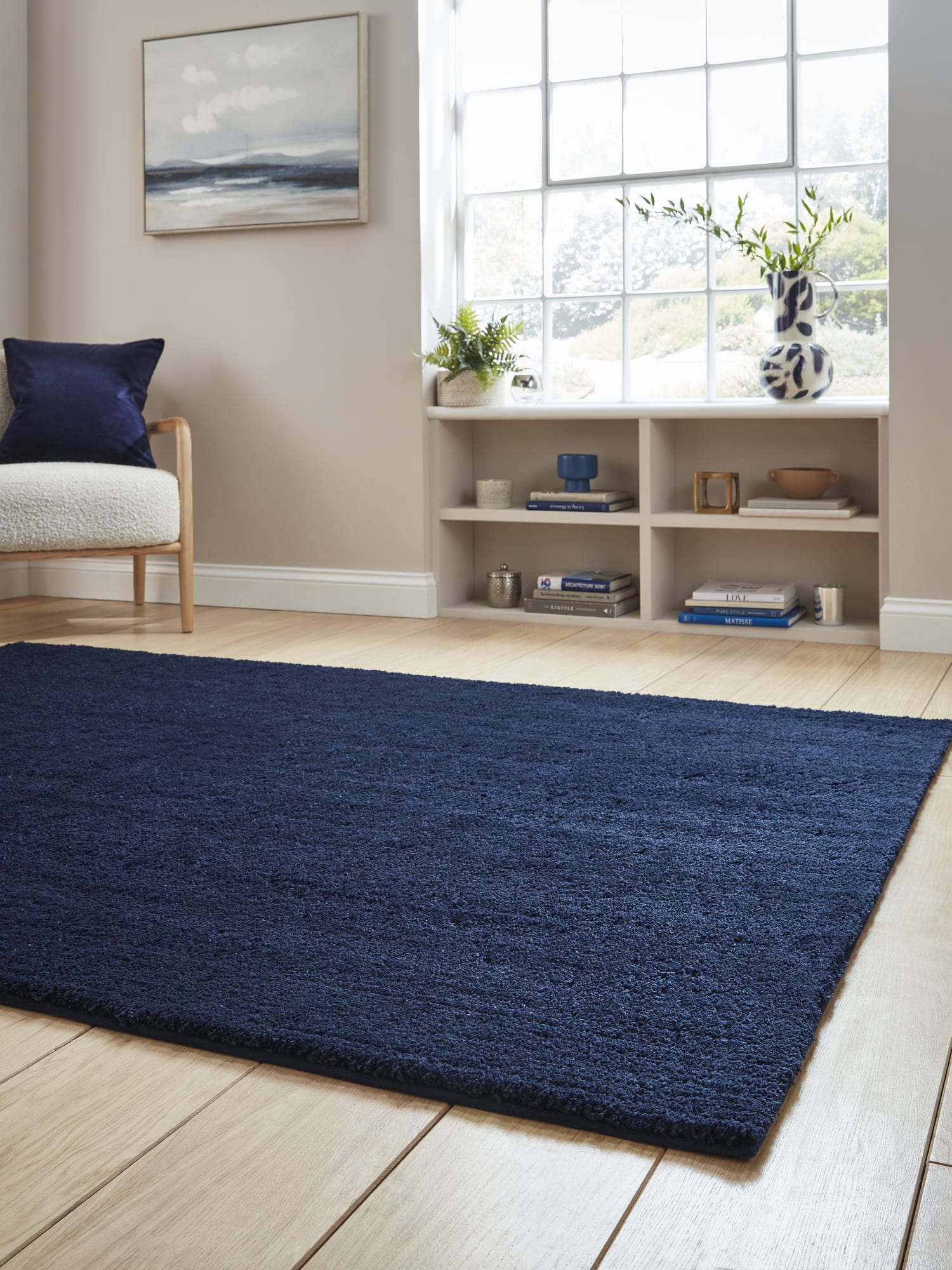 Riviera rectangular rug in navy, at a low angle showing the pile beside a large window.