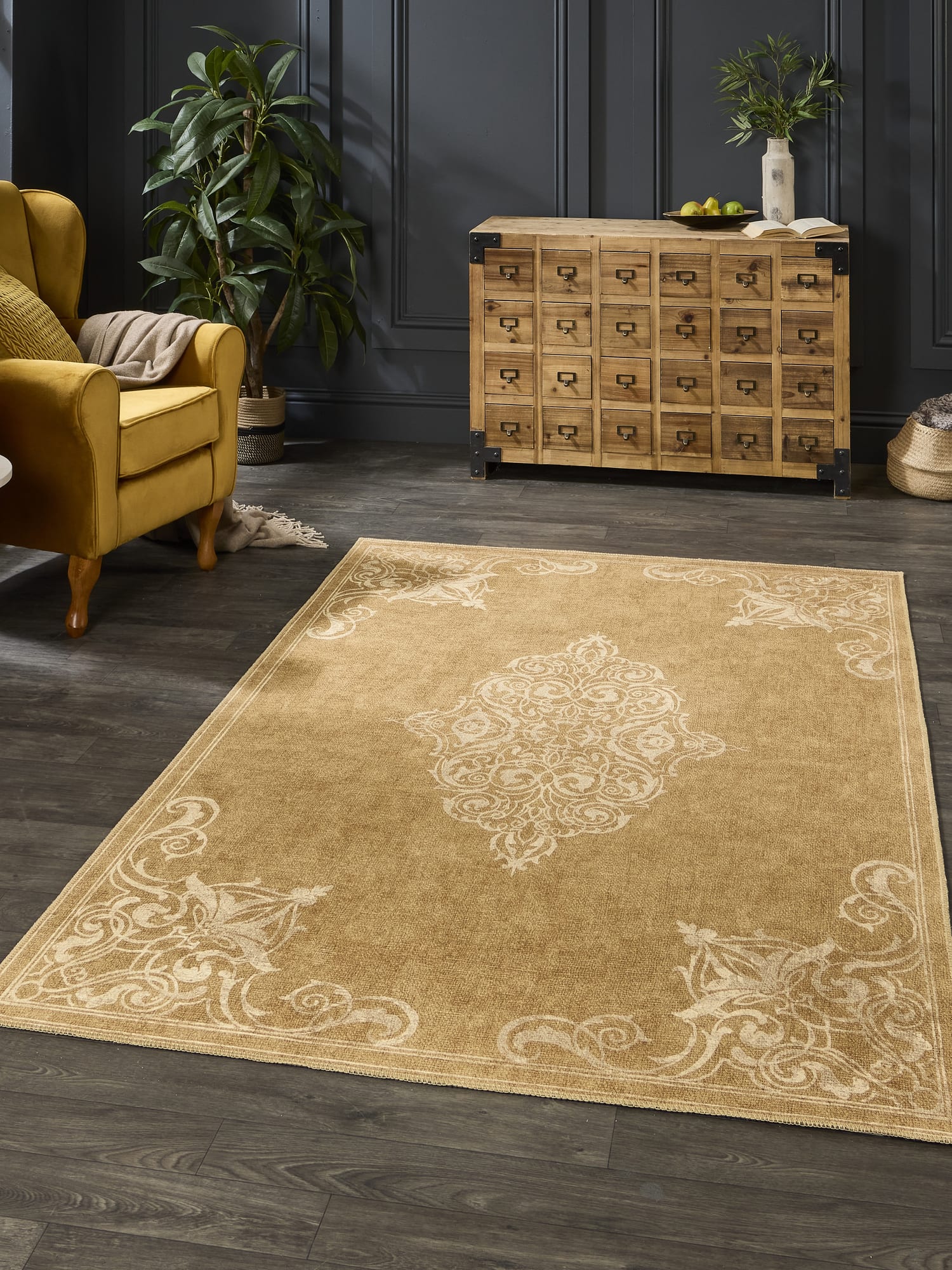 Sarabande rectangular rug in gold, beside an armchair and a many-drawer cabinet.
