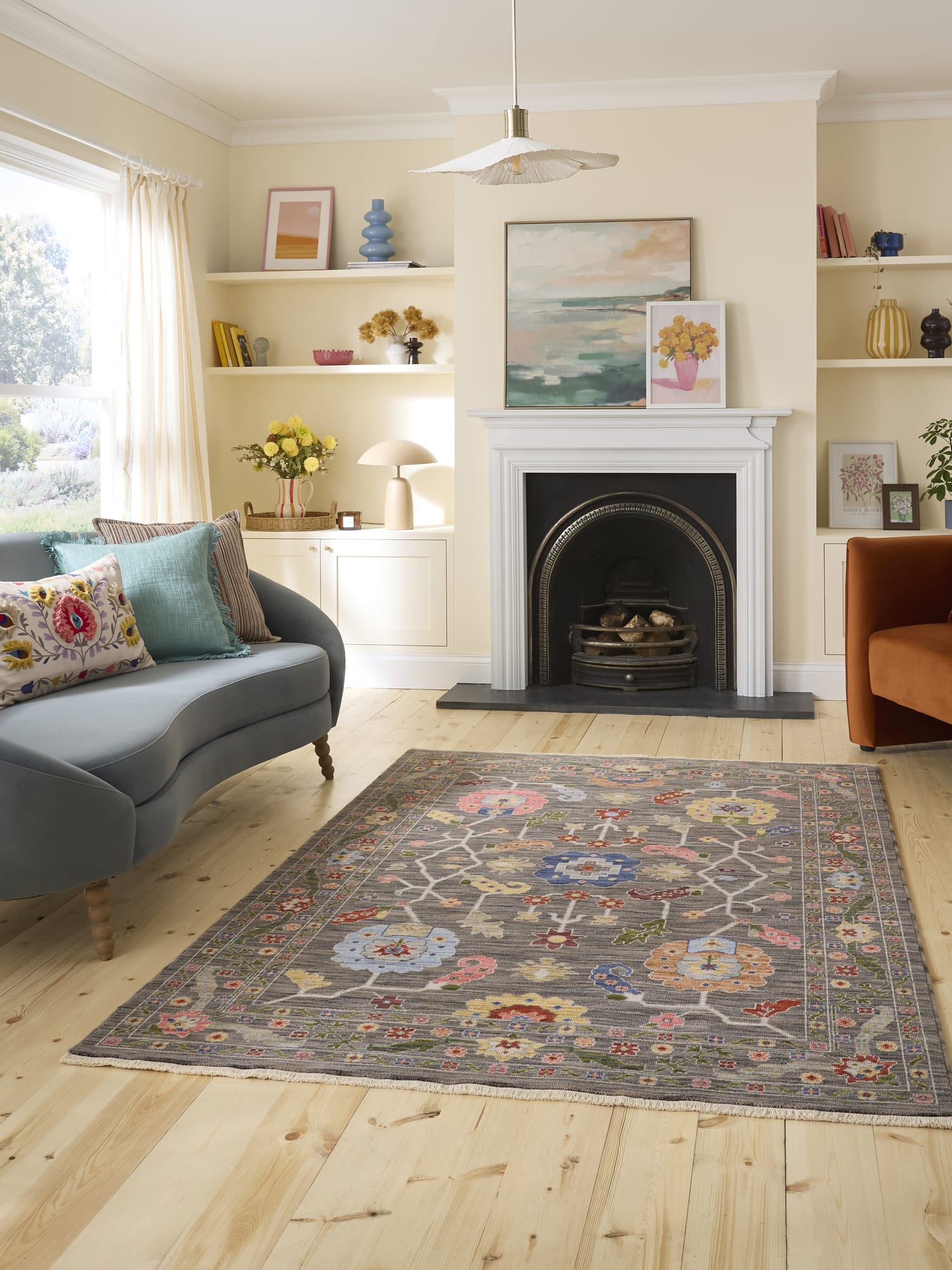Suzani Branching Floral Black/Multi Wool-Blend Rug. Suzani Branching Floral rectangular rug in black and mixed colours, in a living room with a fireplace and display shelves.