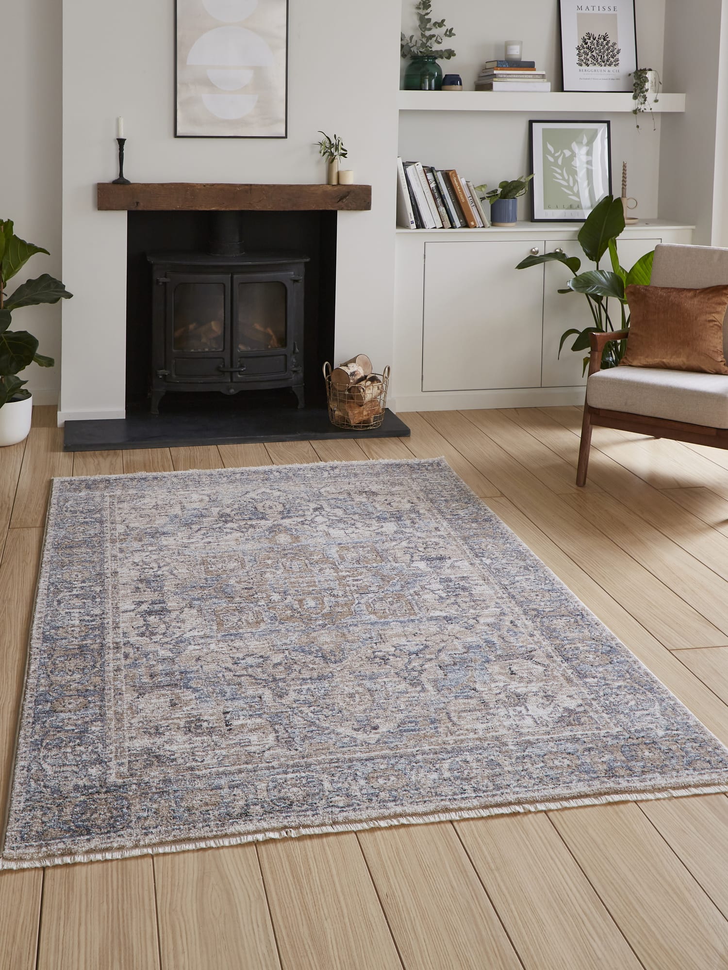 Vintage Medallion rectangular rug in blue, in front of a fireplace beside an armchair.