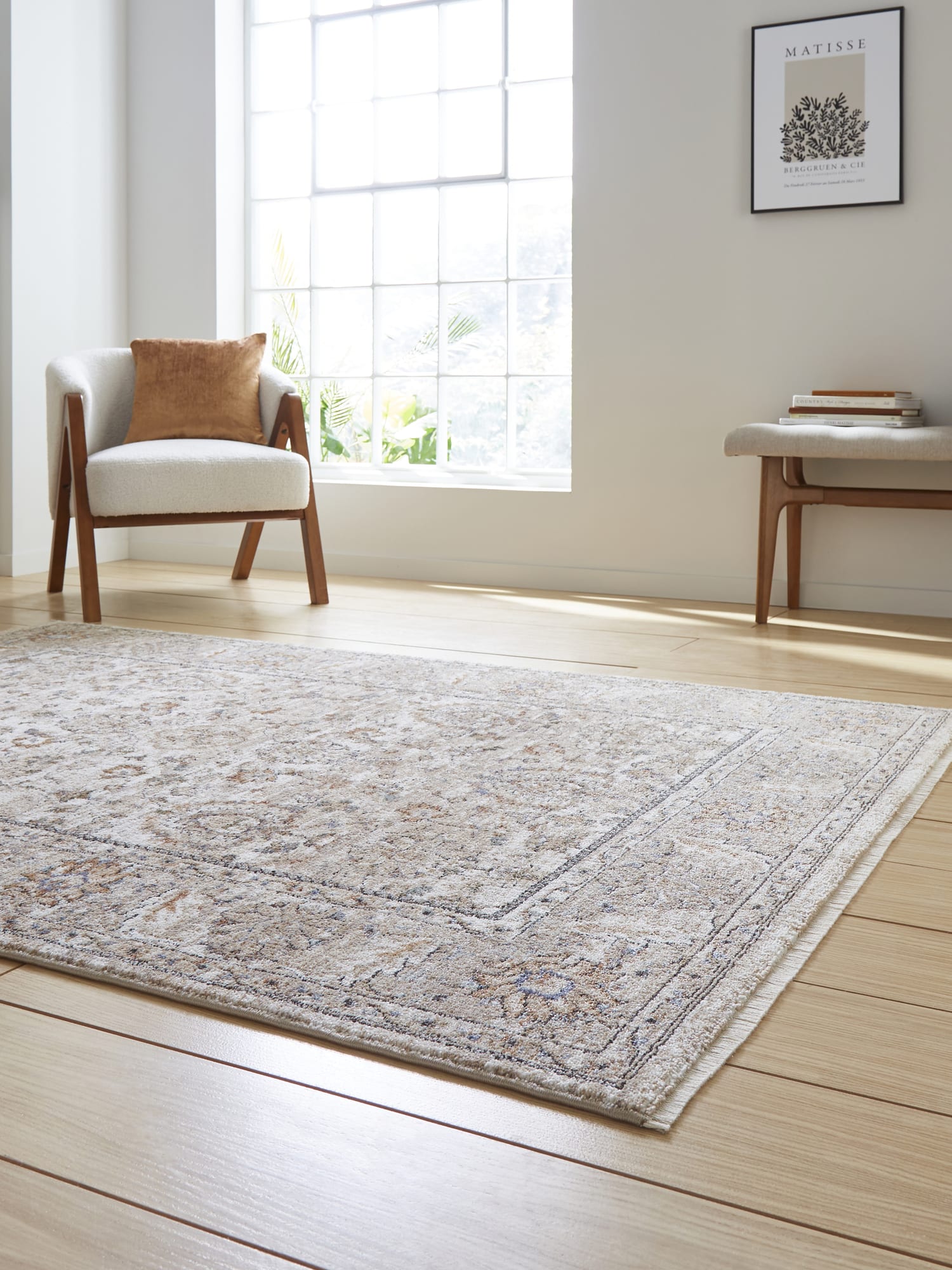 Vintage Ornamental rectangular rug in beige, at a low angle beside a large window.