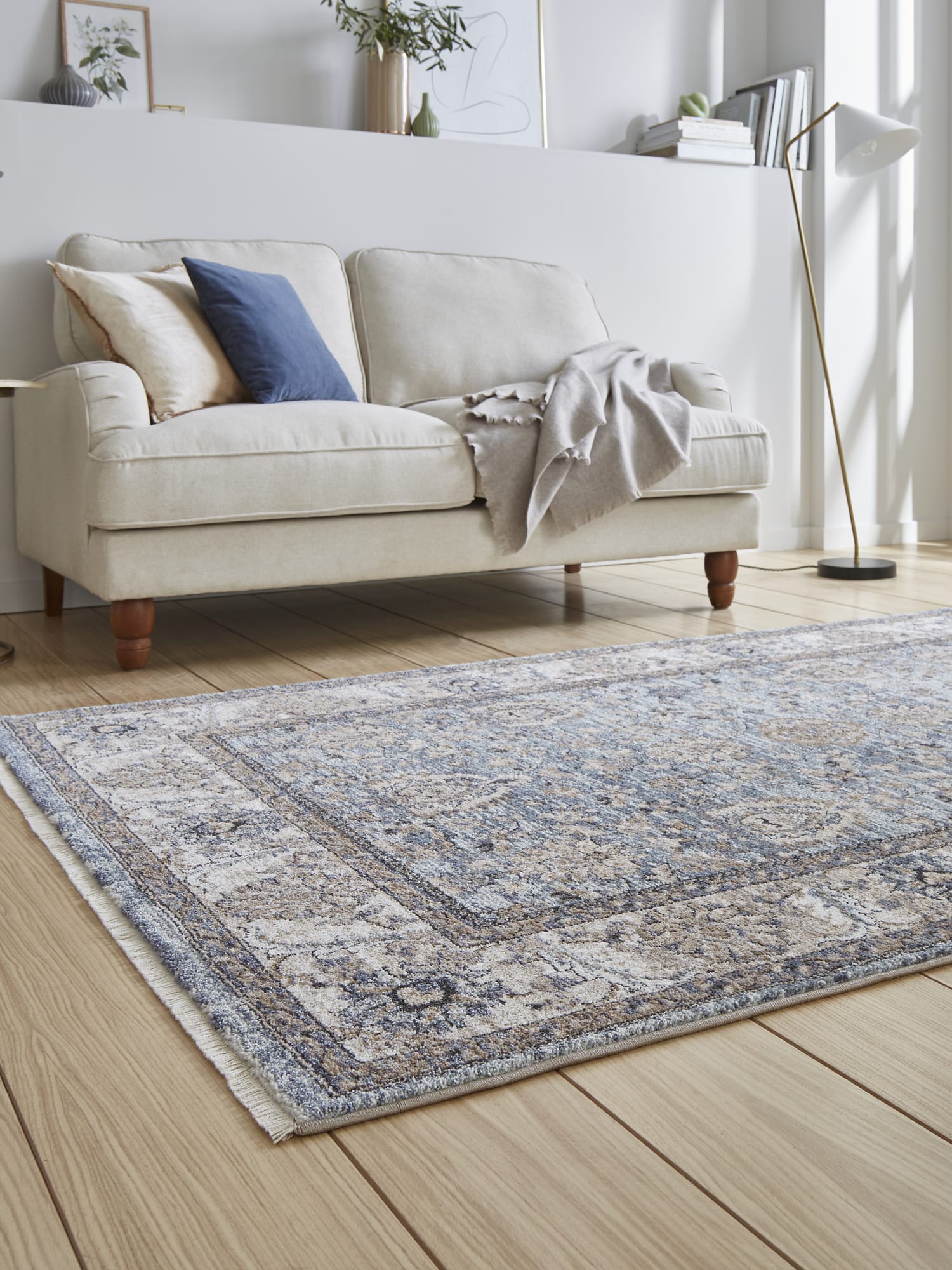 Vintage Ornamental rectangular rug in blue, at a low angle in front of a pale sofa.