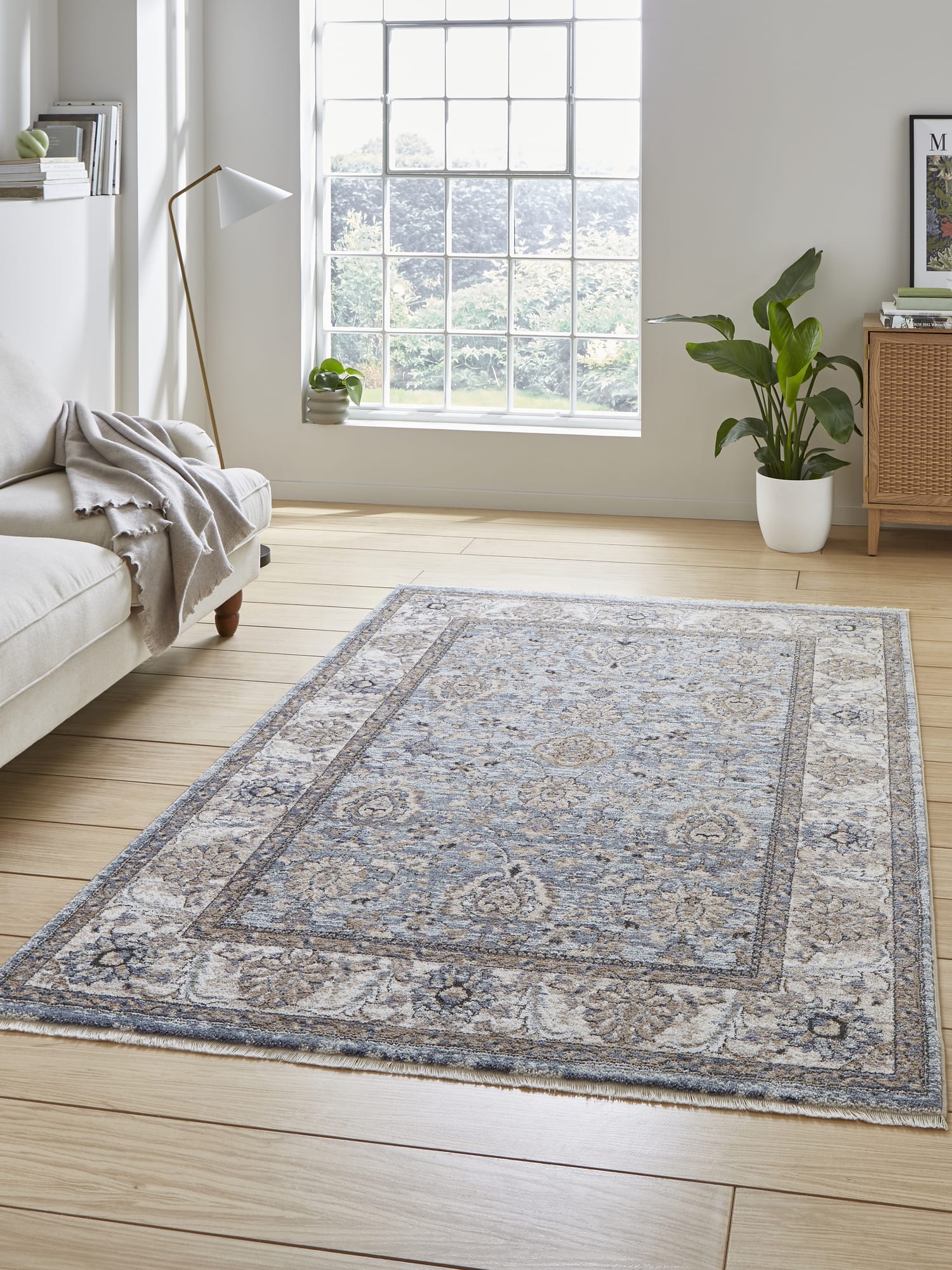 Vintage Ornamental rectangular rug in blue, beside a pale sofa and a large window.