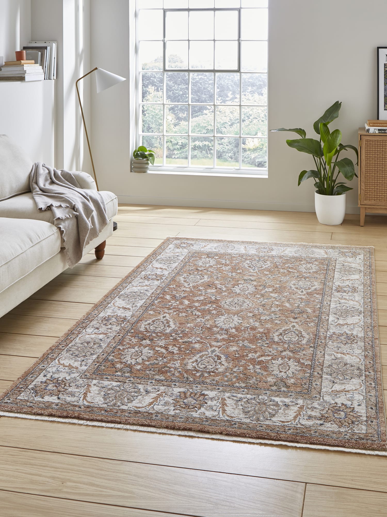 Vintage Ornamental rectangular rug in terracotta, beside a pale sofa and a large window.