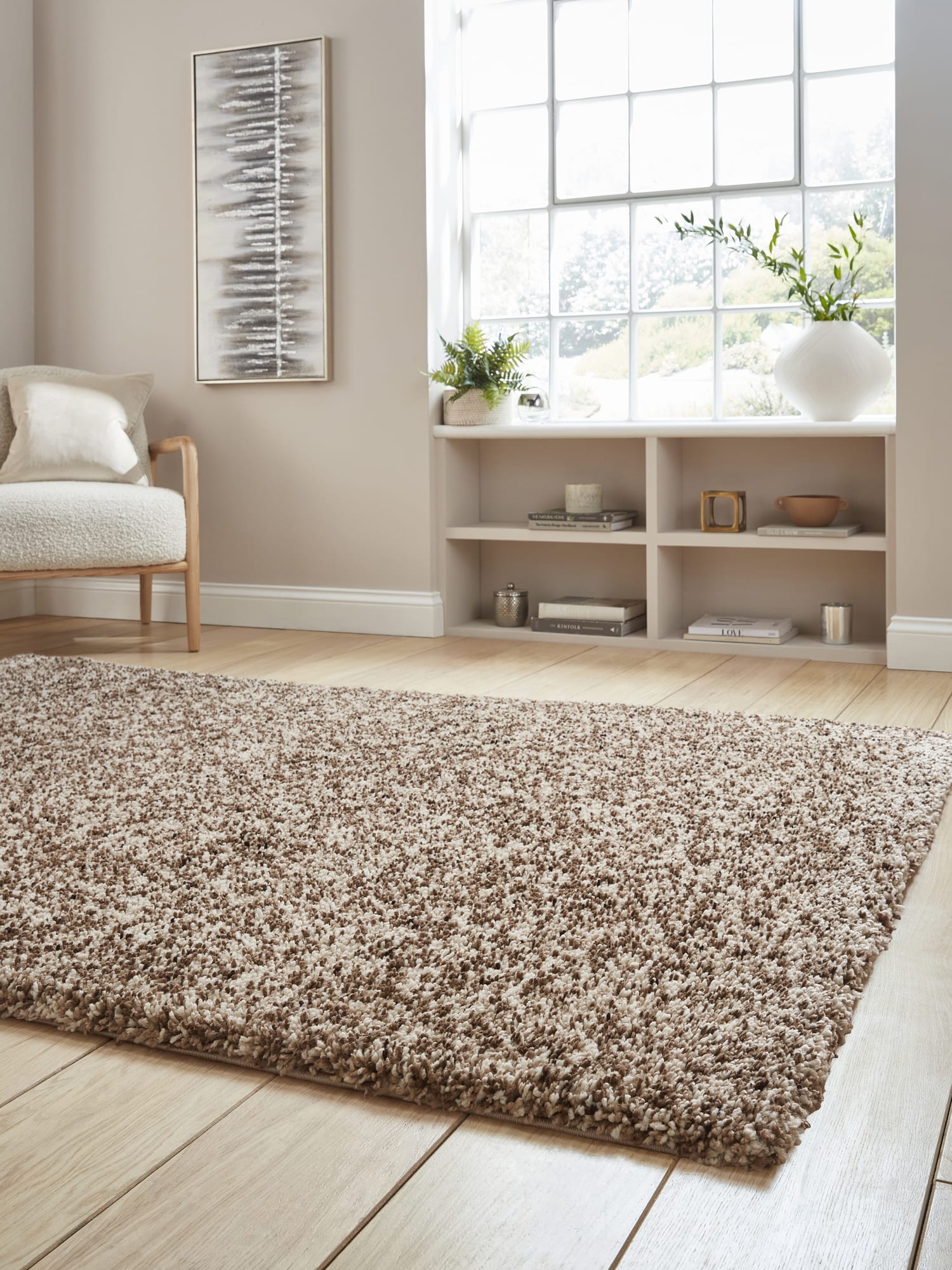 Vista rectangular rug in beige, at a low angle showing the shaggy pile beside a window.