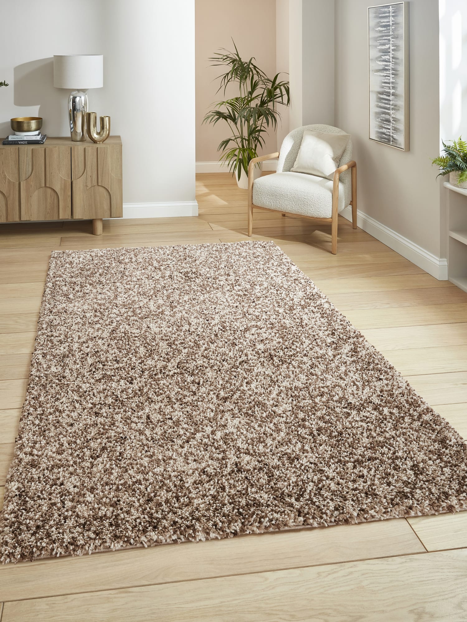 Vista rectangular rug in beige, beside an armchair and a wooden cabinet.