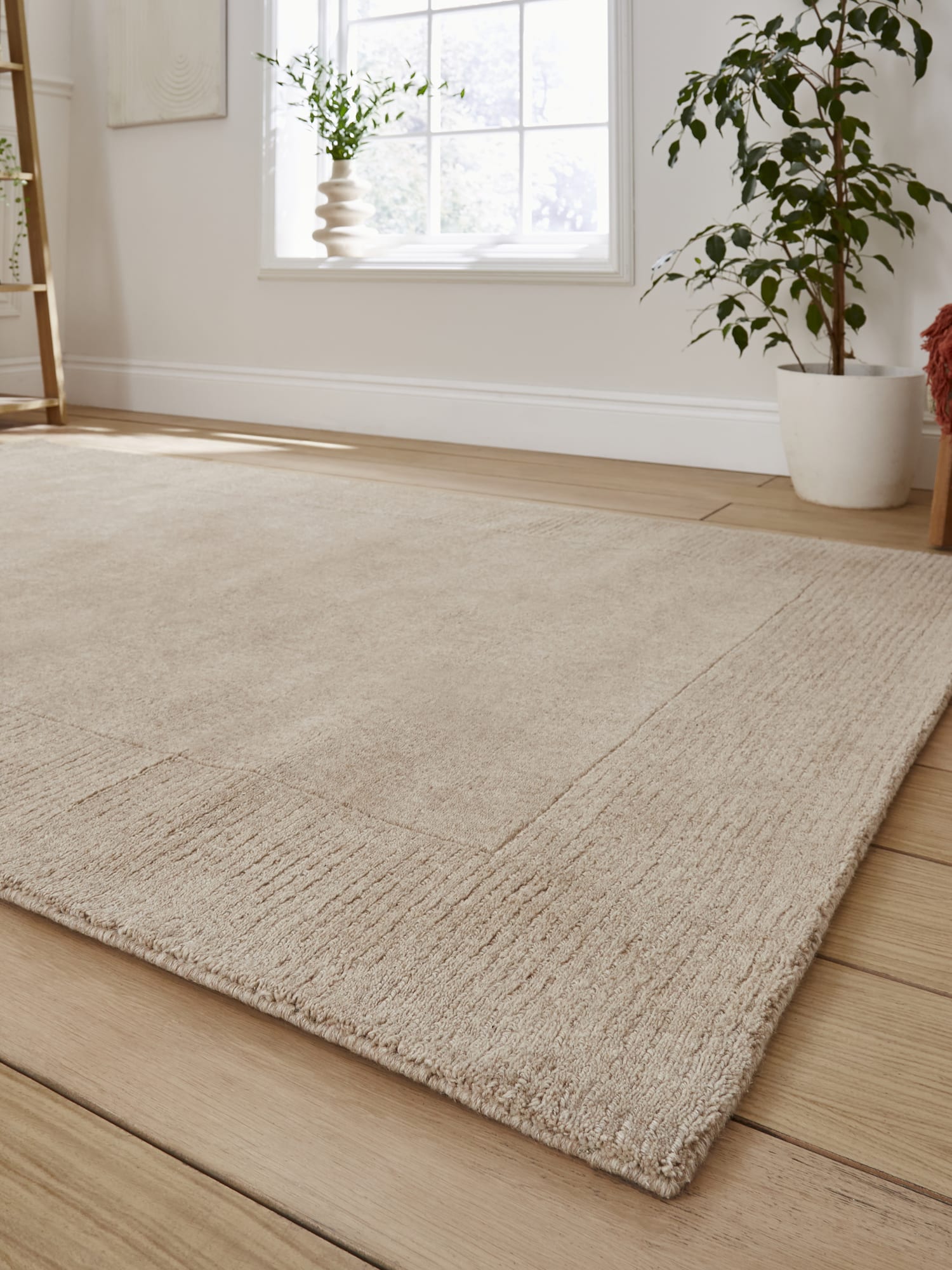 Windsor Border rectangular rug in natural, at a low angle showing the tonal border and corner.