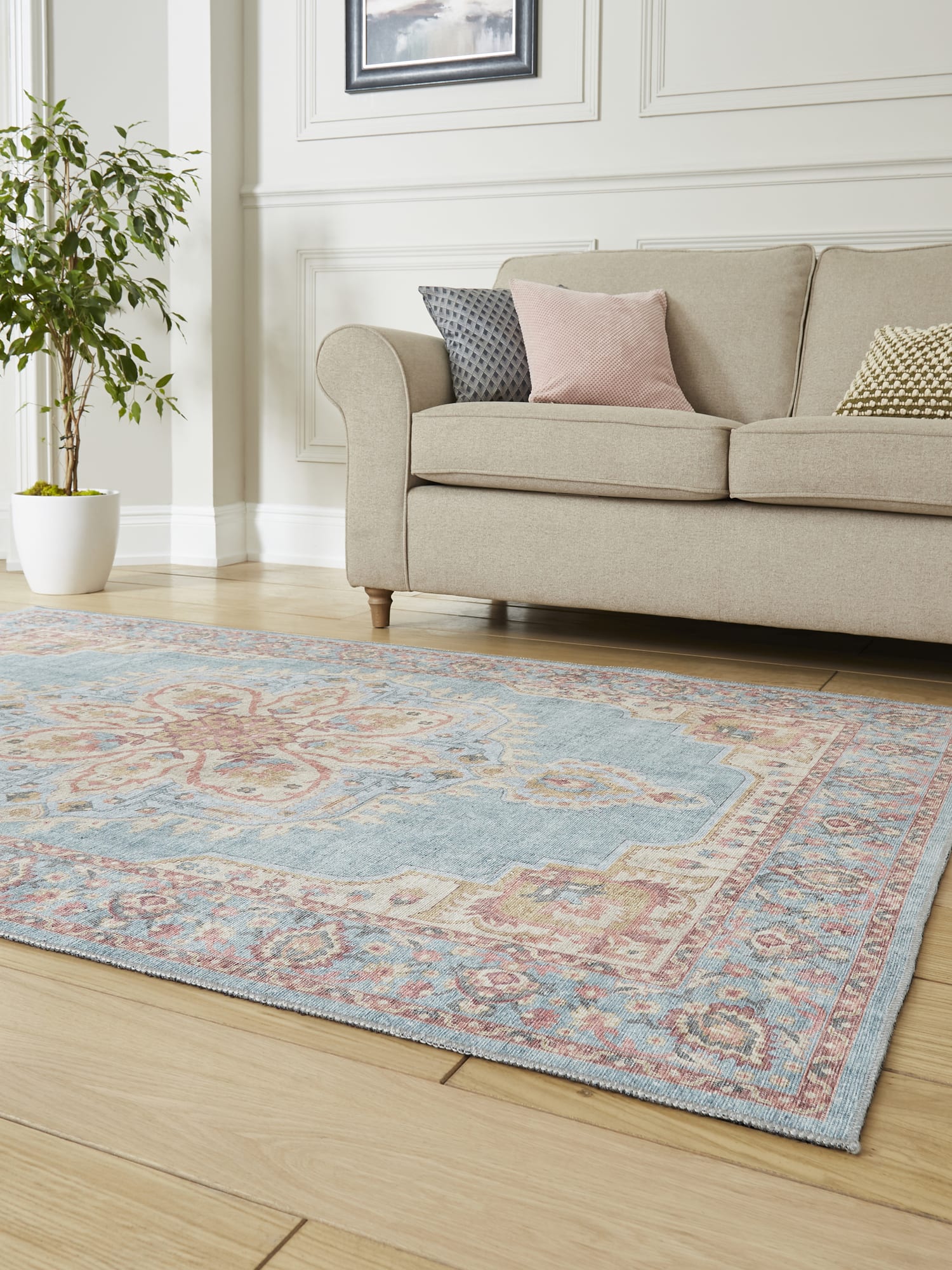 Zahra Washable rectangular rug in blue and beige, at a low angle in front of a pale sofa.
