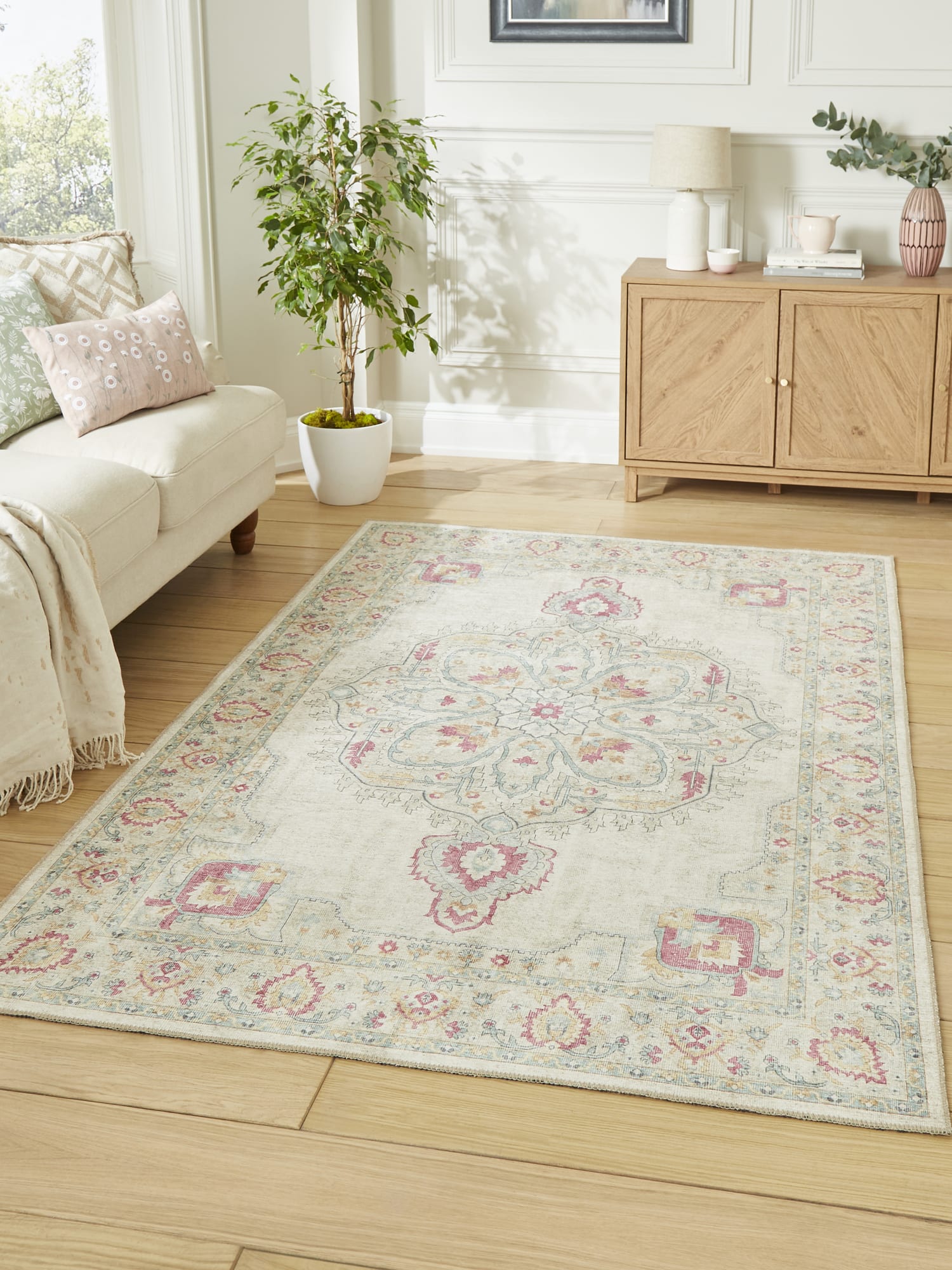 Zahra Washable rectangular rug in cream, beside a pale sofa and a wooden cabinet.